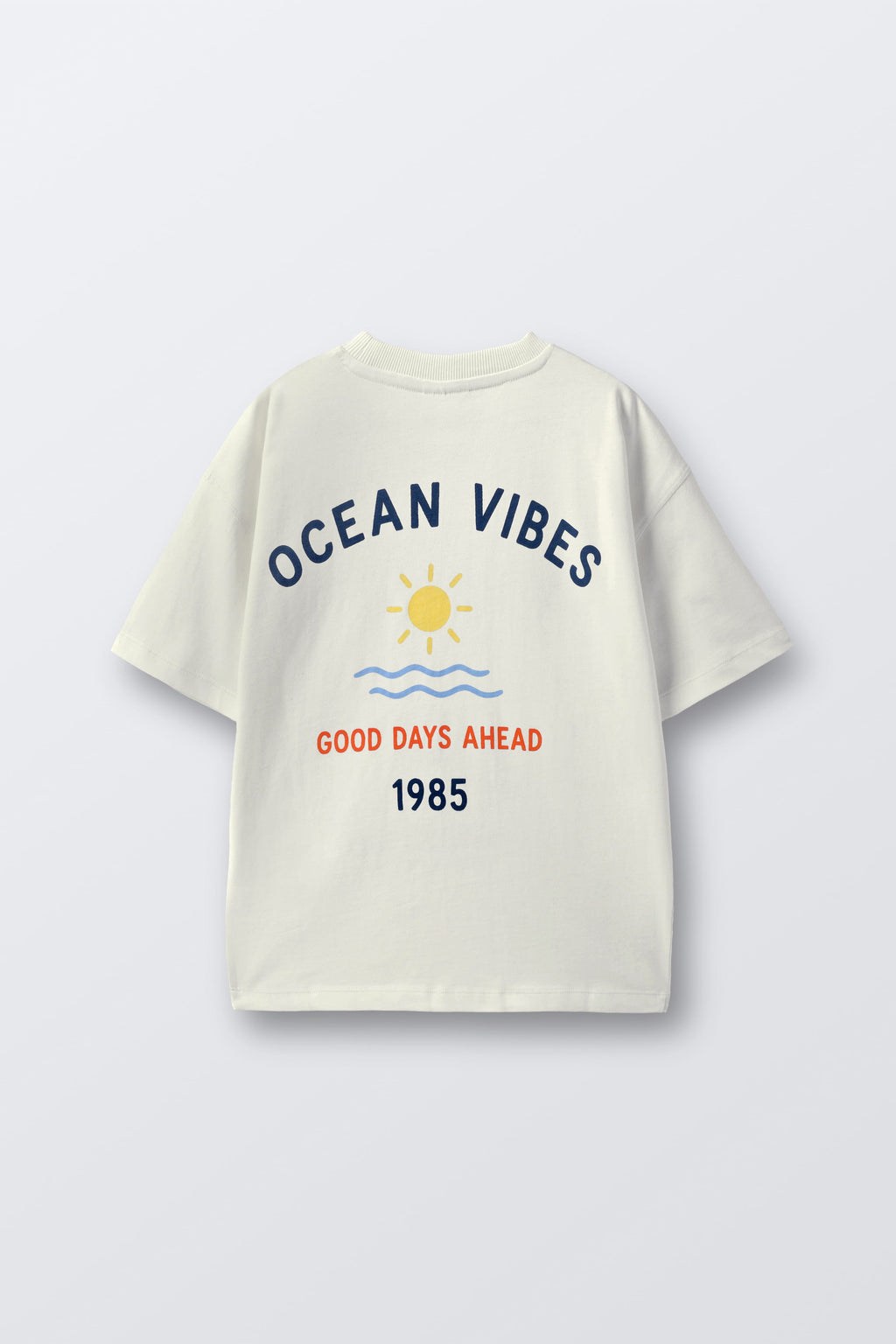 Off-white comfort tee with back “Ocean Vibes” print, sun, waves, and 1985