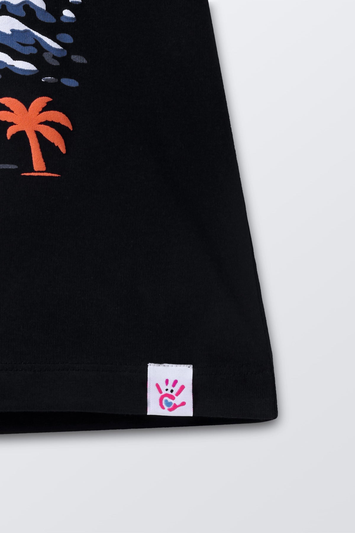Black tee hem close-up with small white tag label near bottom