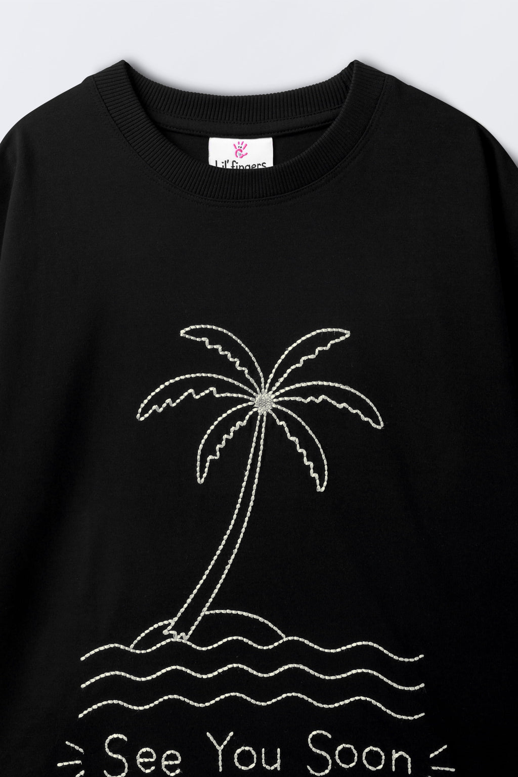Black oversized T-shirt close-up showing crew neck and palm tree graphic