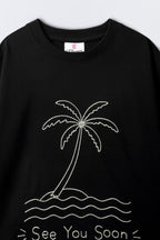 Black oversized T-shirt close-up showing crew neck and palm tree graphic