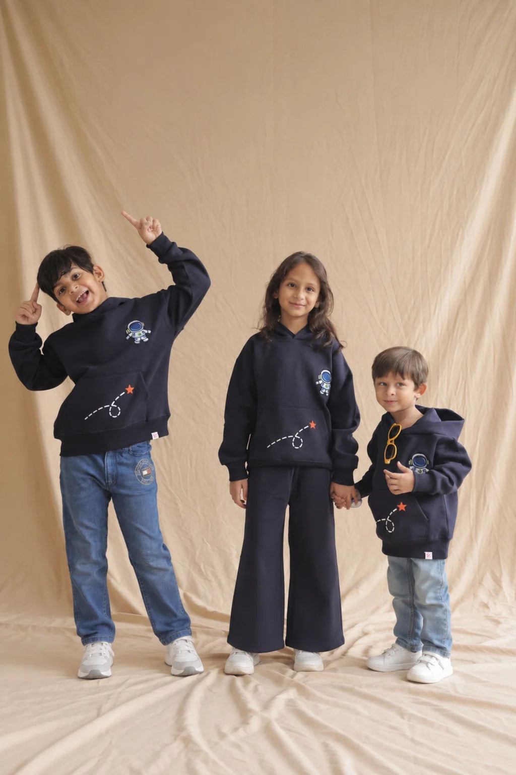Navy astronaut hoodie worn by three kids with front embroidery and graphic print