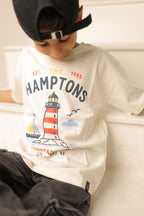 Off-white comfort tee with “The Hamptons” lighthouse graphic worn by a child