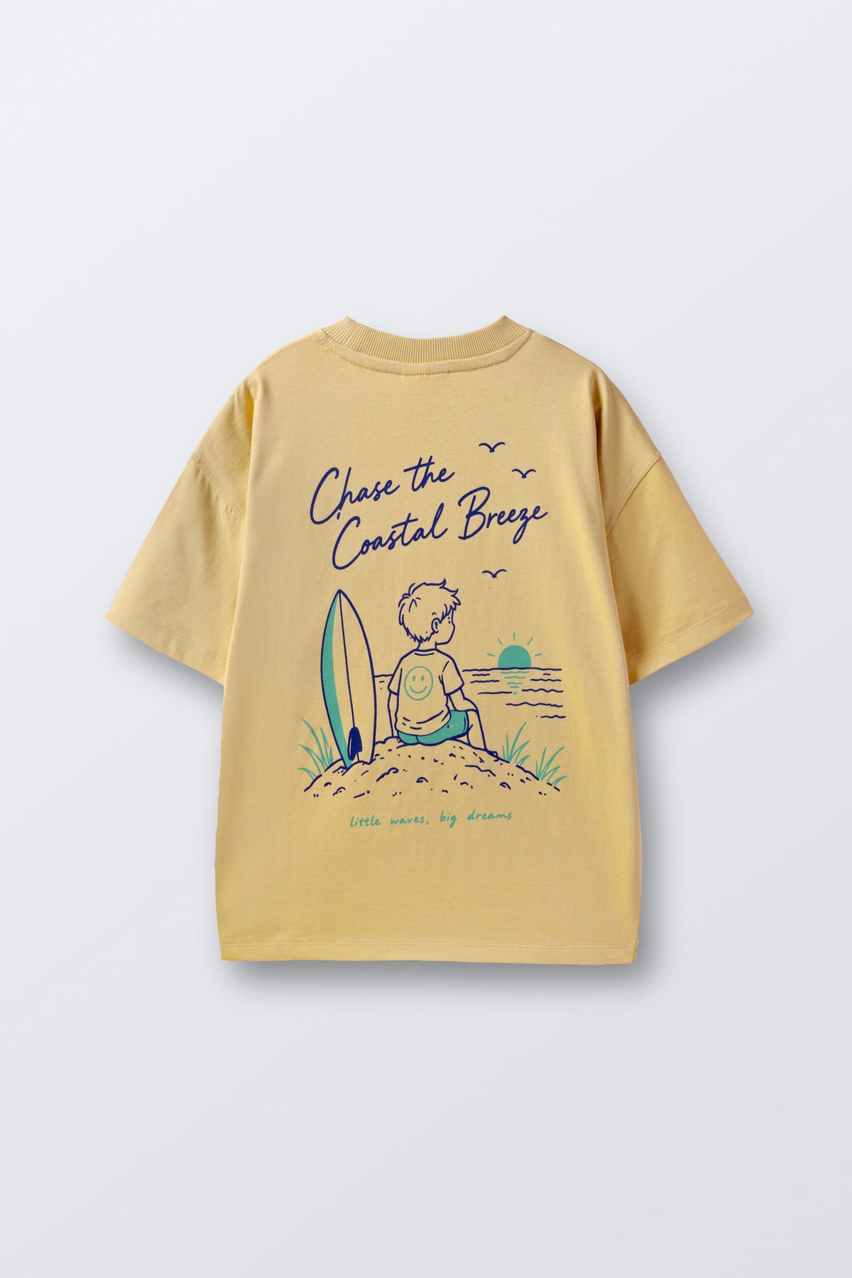 Sand yellow graphic tee with surf-kid illustration and 'Chase the Coastal Breeze' text.