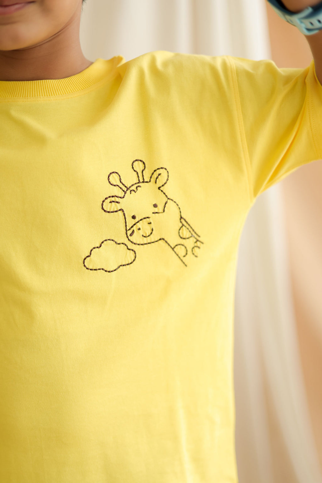 Yellow kids comfort tee close-up of giraffe and cloud stitched embroidery