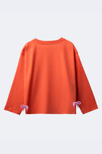 Girl’s coral long-sleeve T-shirt with bow ties at hem, embroidered rainbow and clouds