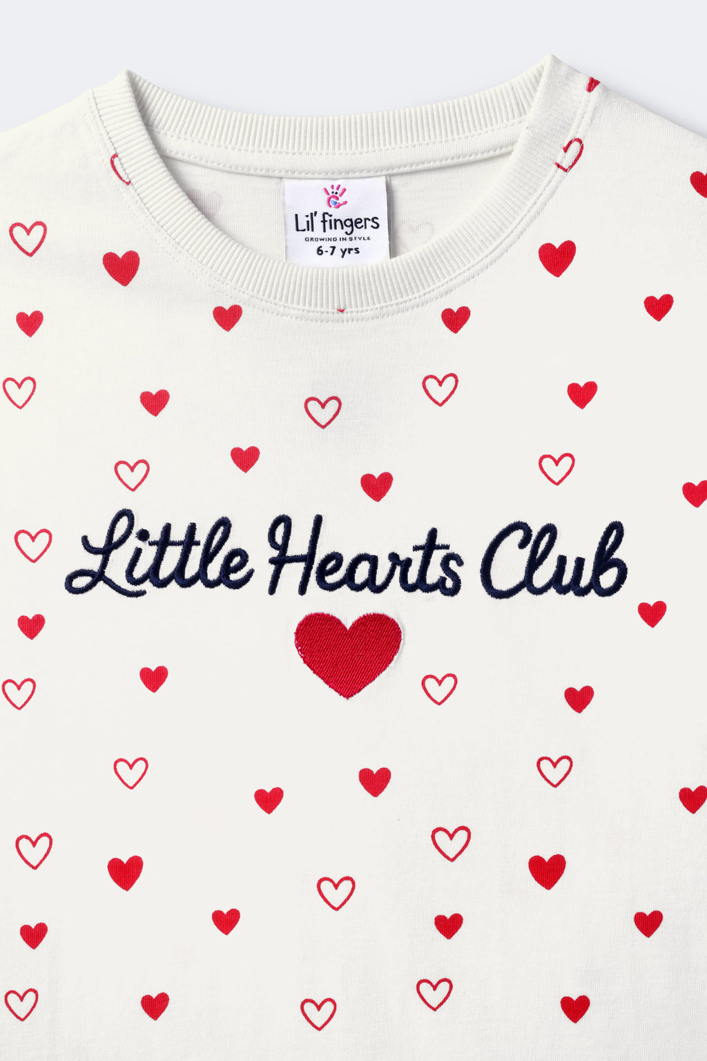 Off-white comfort tee close-up: red hearts with 'Little Hearts Club' script on chest