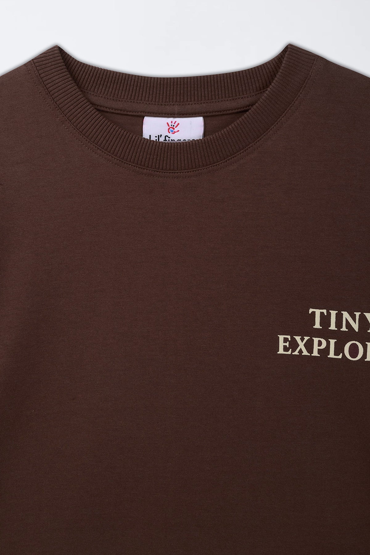 Brown crew-neck kids' T-shirt close-up of “TINY EXPLORER” front print