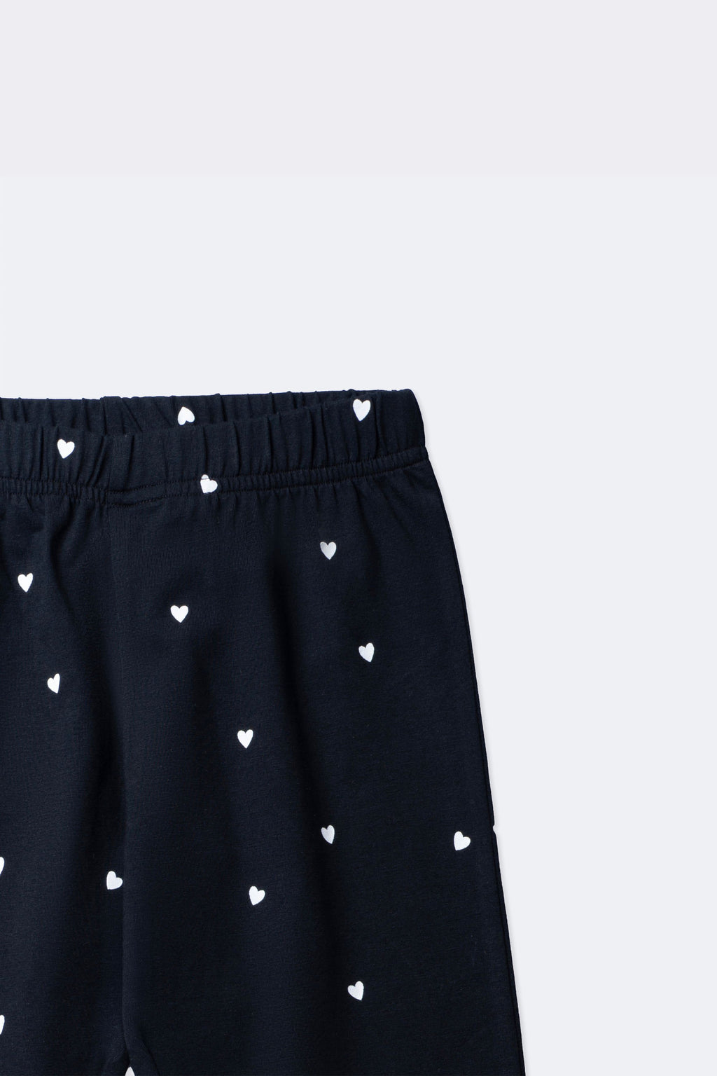 Black leggings close-up: elastic waistband and mini white heart all-over print