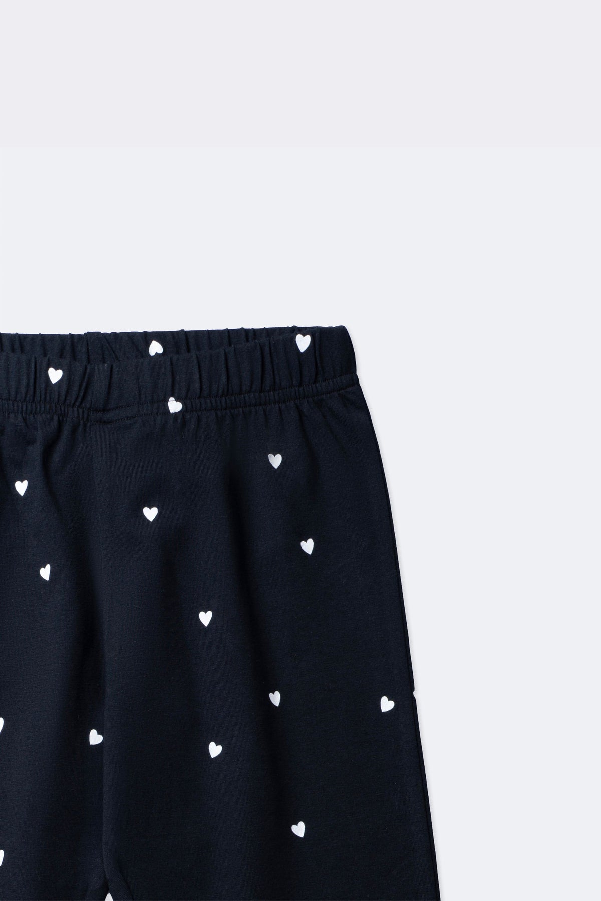 Black leggings close-up: elastic waistband and mini white heart all-over print