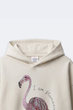 Ivory cream girls hoodie with embellished flamingo and arched text near chest
