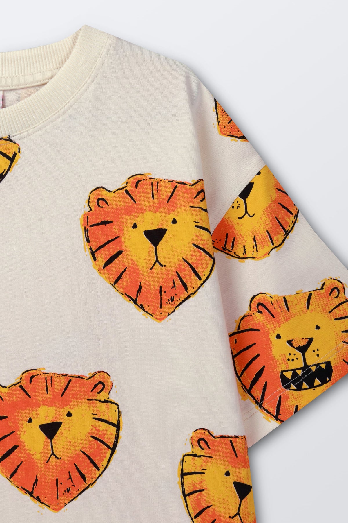 White t-shirt with orange lion face print, close-up on chest and sleeve