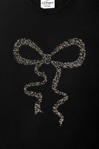 Black long-sleeve tee with centered gold-toned bead bow and ribbon drops