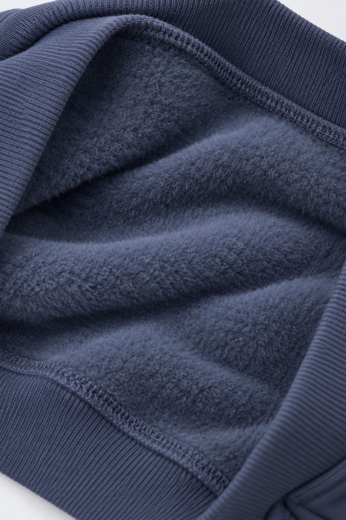 Denim blue fleece sweatshirt fabric close-up with ribbed cuffs and hem