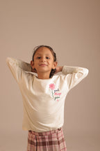 Off-white long-sleeve tee with small floral “good things grow” graphic on the chest.