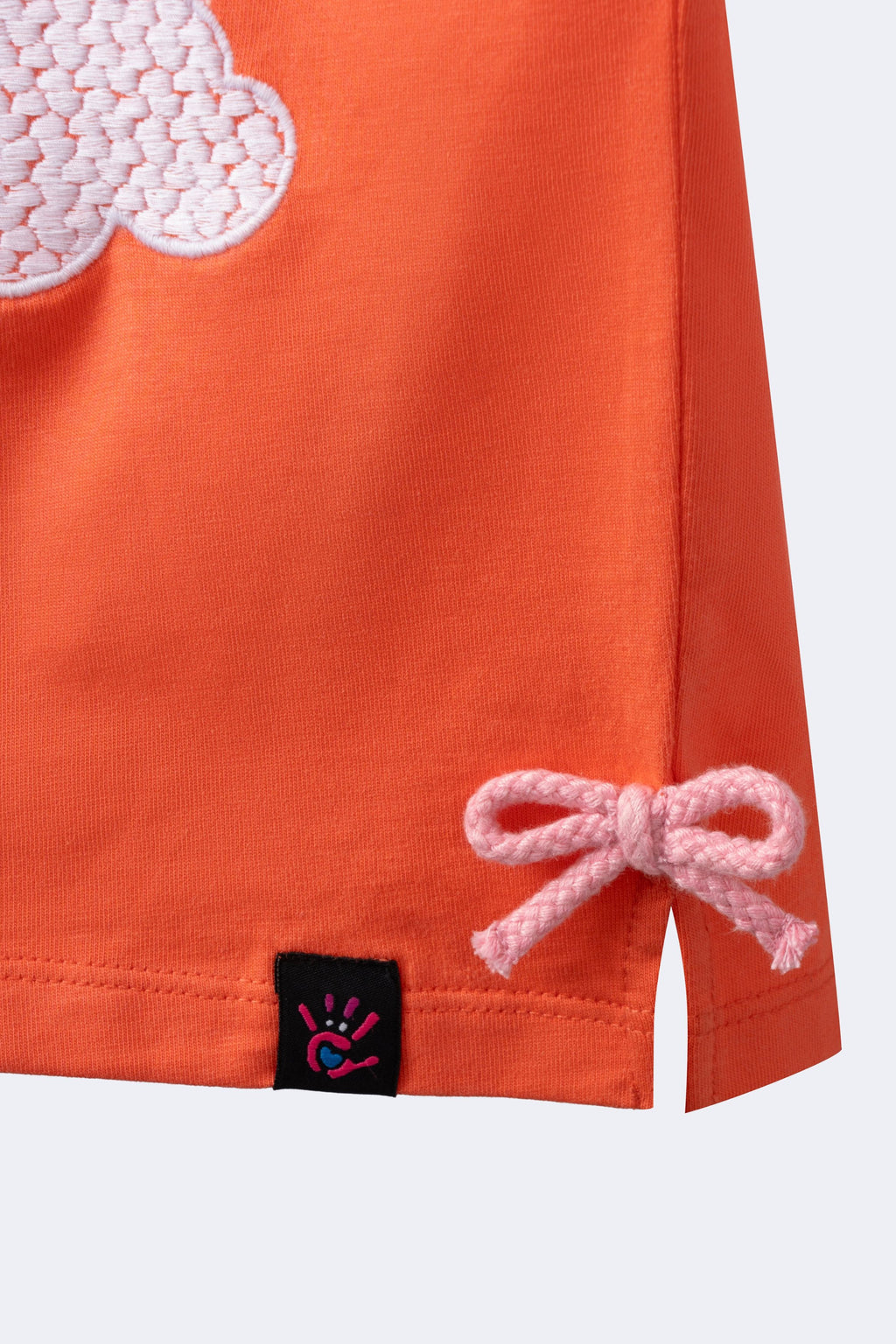 Girl’s coral T-shirt hem detail with bow tie and small black tag