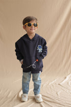 Navy hoodie on child with astronaut embroidery and rocket-dash graphic on front