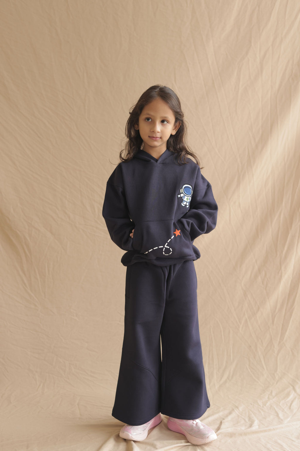 Navy hoodie worn by child with astronaut embroidery and rocket-dash graphic