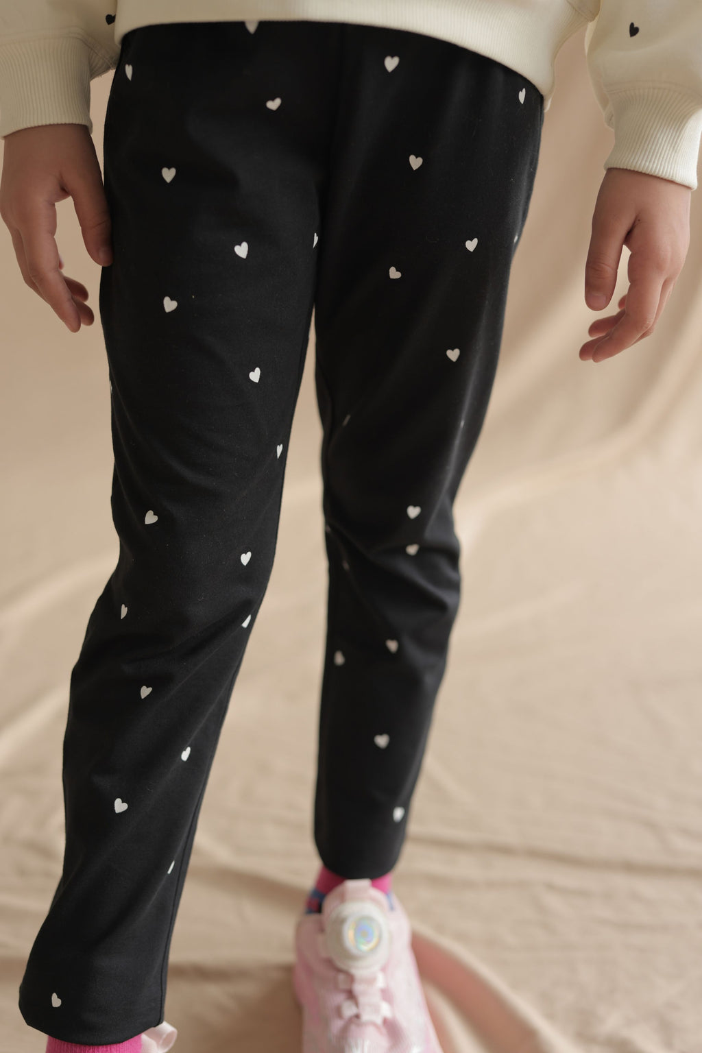 Black stretch leggings with mini white hearts, full leg view