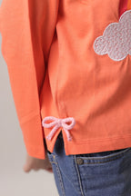 Coral long-sleeve T-shirt sleeve and hem close-up with bow tie detail