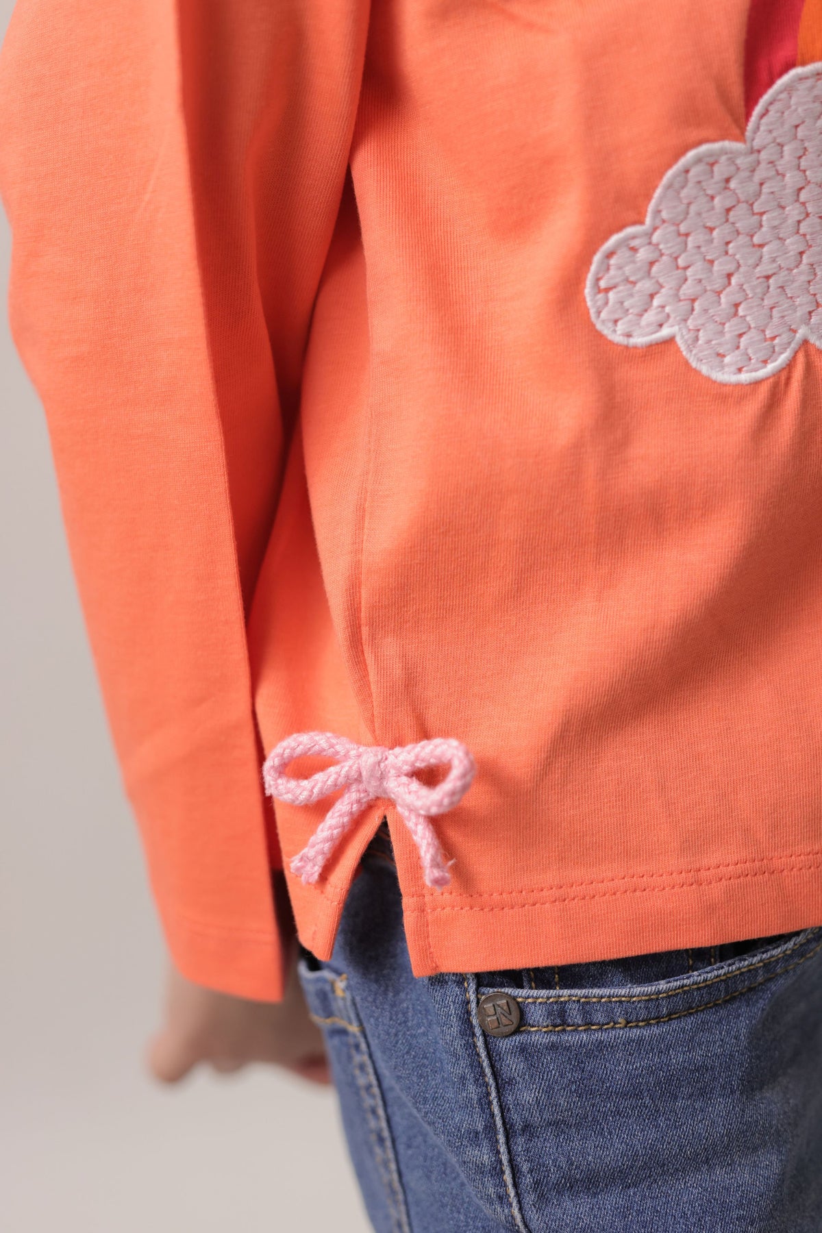 Coral long-sleeve T-shirt sleeve and hem close-up with bow tie detail