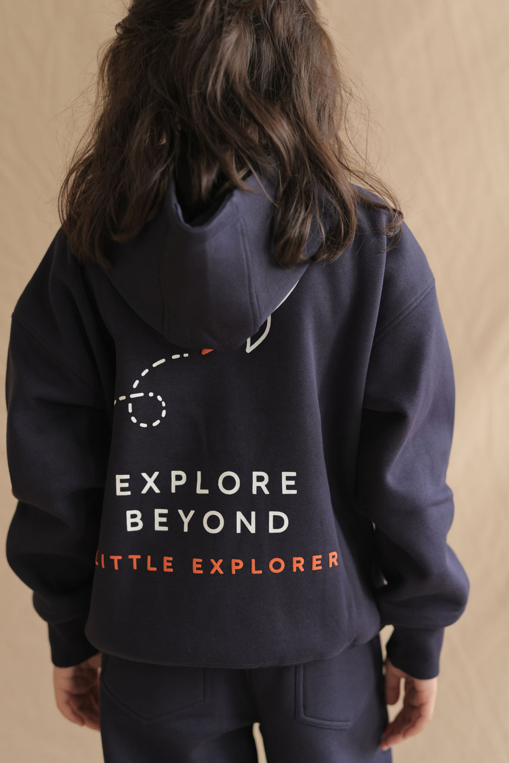 Navy hoodie close-up, back view: Explore Beyond with Little Explorer print