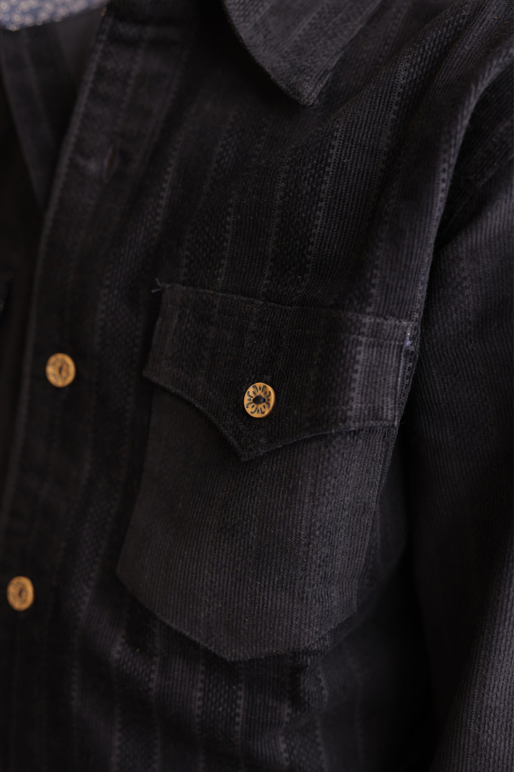 Navy corduroy shirt front pocket with gold button detail and textured striped fabric