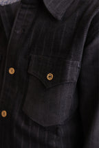 Navy corduroy shirt front pocket with gold button detail and textured striped fabric