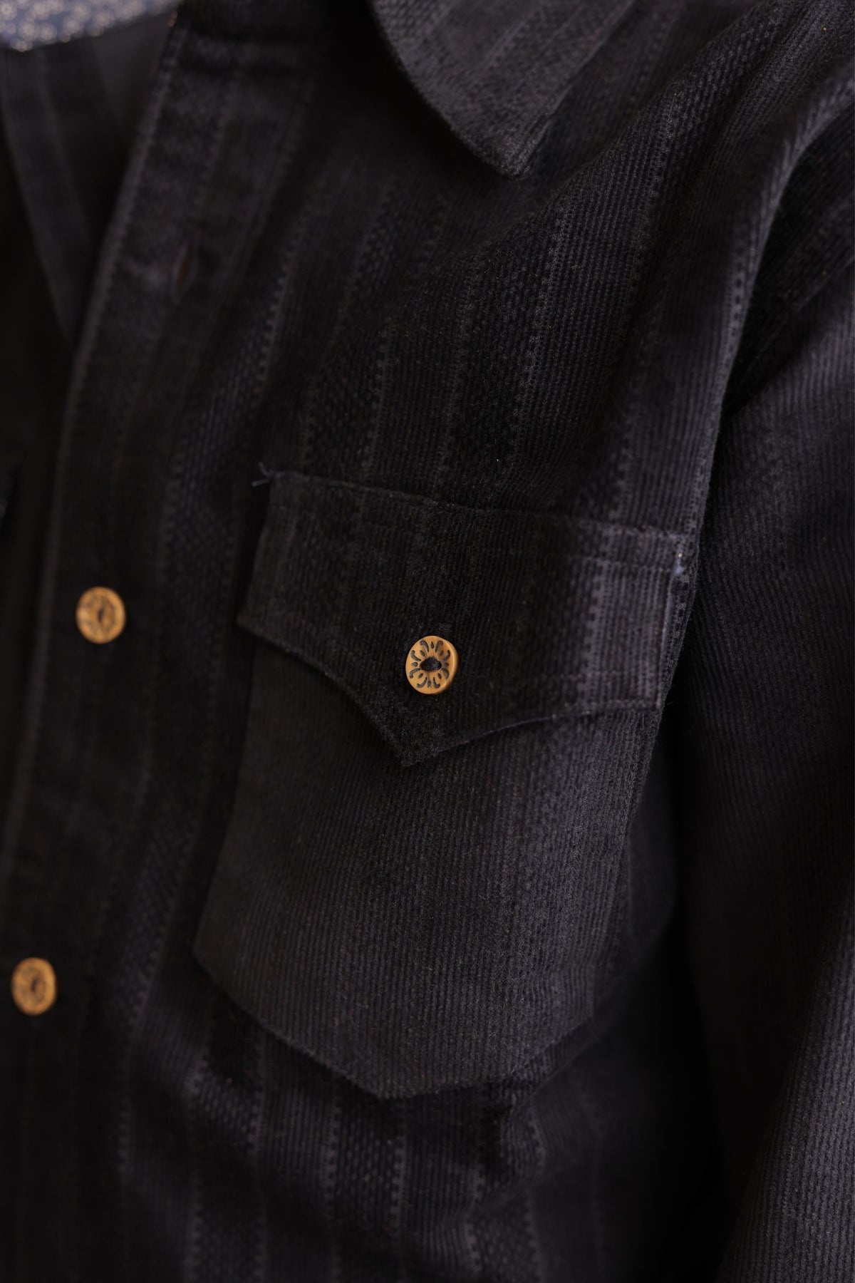 Navy corduroy shirt front pocket with gold button detail and textured striped fabric