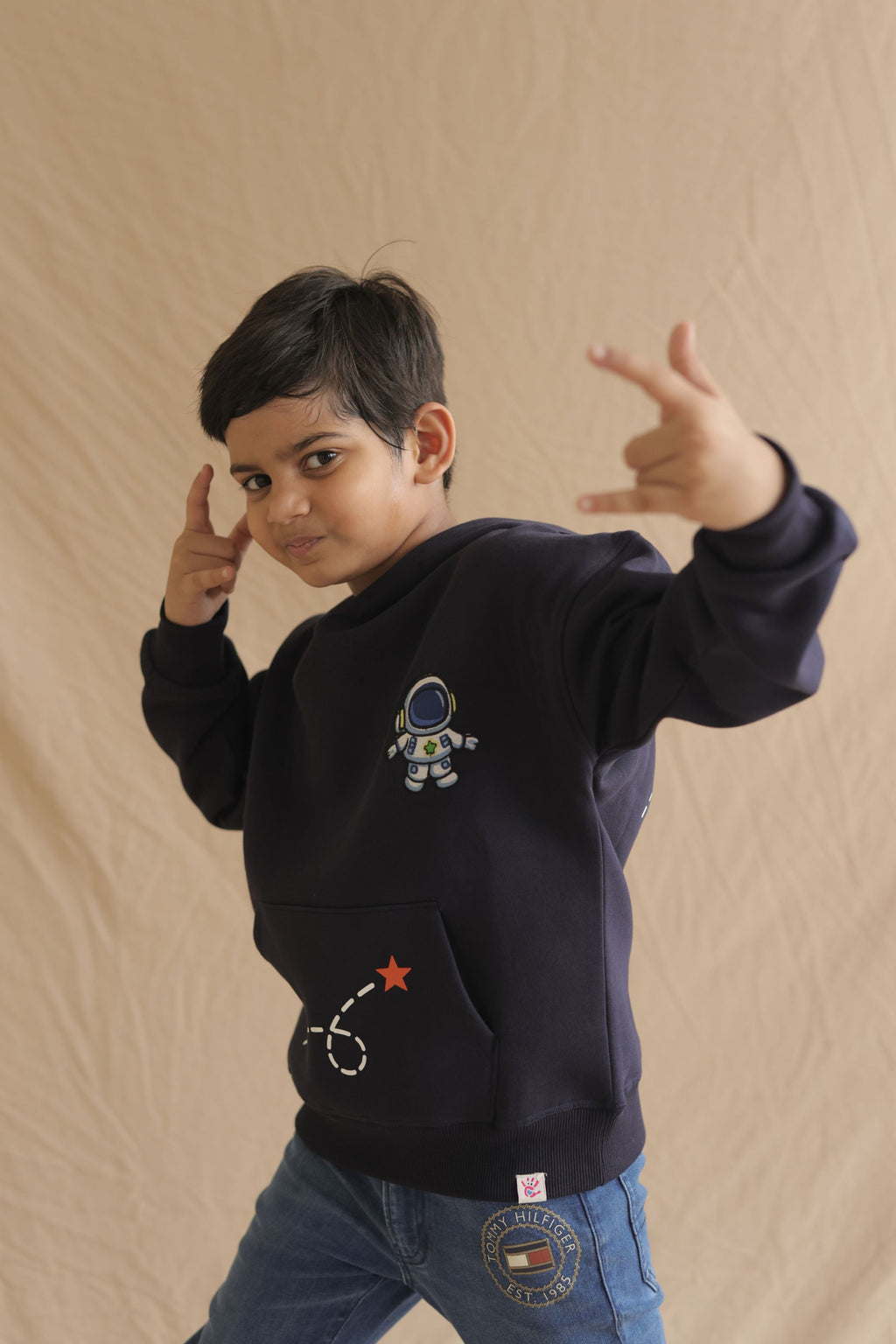 Navy hoodie worn by child with astronaut chest embroidery and star rocket graphic