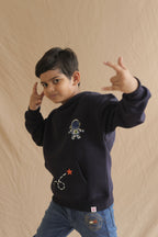 Navy hoodie worn by child with astronaut chest embroidery and star rocket graphic