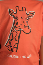 Orange comfort tee close-up with embroidered giraffe and 'EXPLORE THE WILD' text
