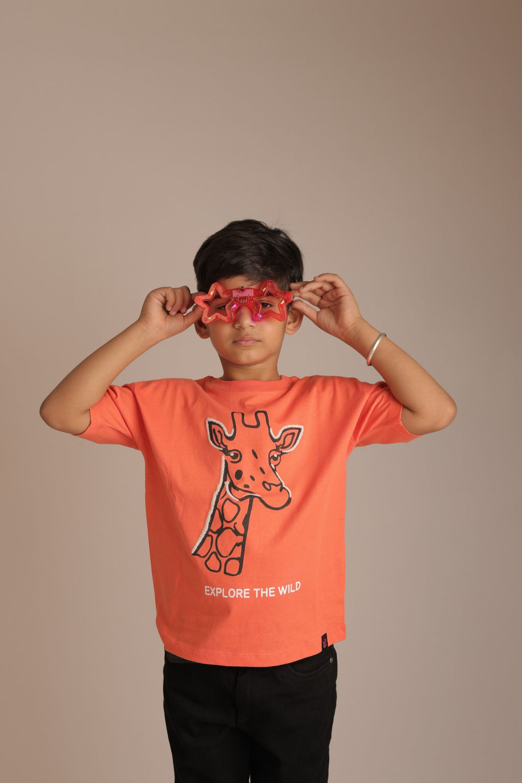 Orange comfort tee with embroidered giraffe graphic and 'EXPLORE THE WILD' text (worn)