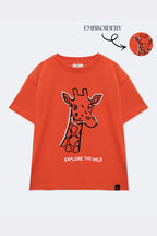 Orange comfort tee with embroidered giraffe outline and 'EXPLORE THE WILD' text