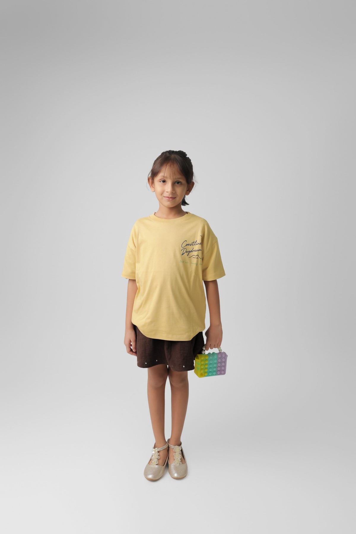 Kids sand yellow graphic comfort tee with 'Chase the Coastal Breeze' logo print.