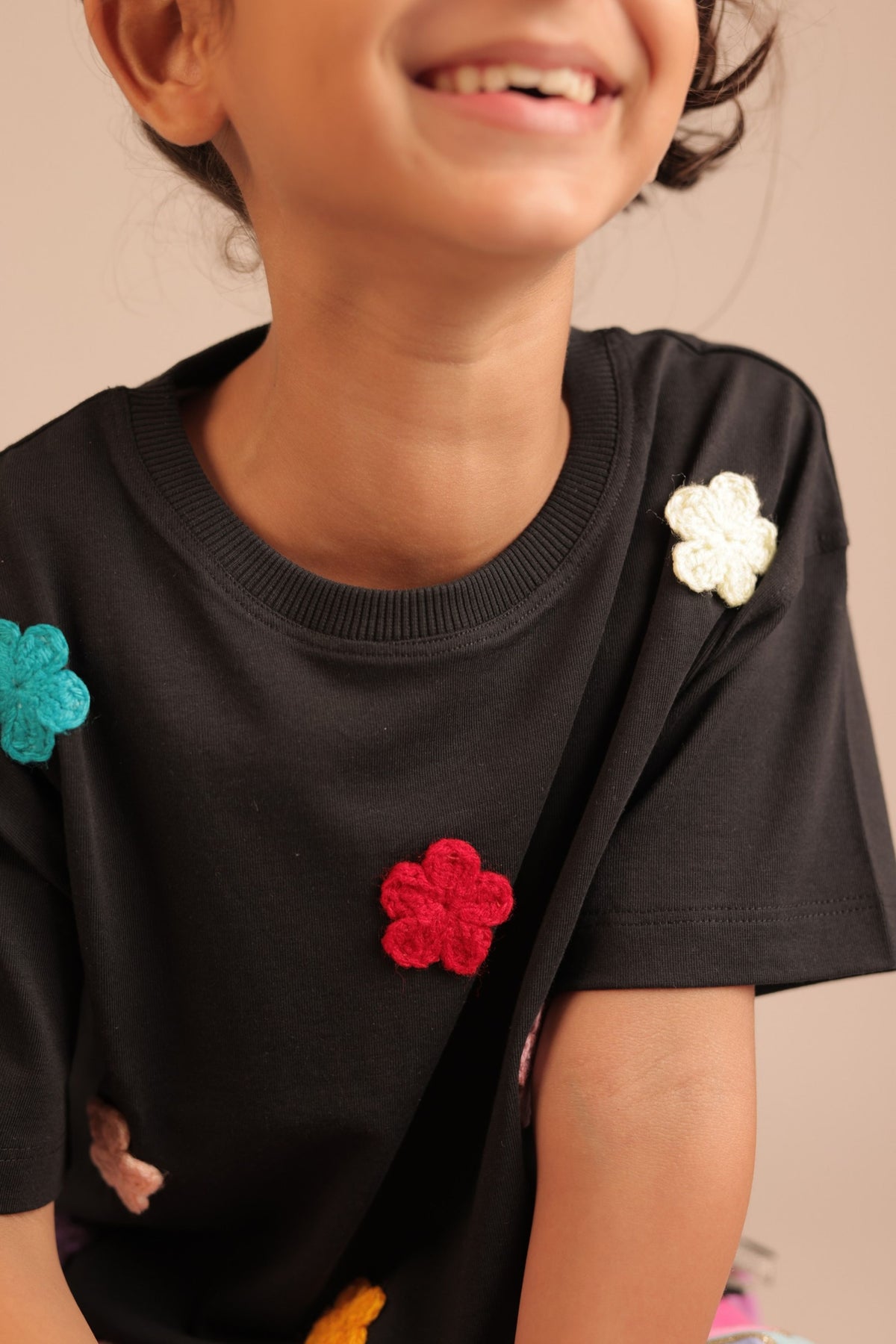 Black tee with colorful crochet flower appliques on front and shoulder