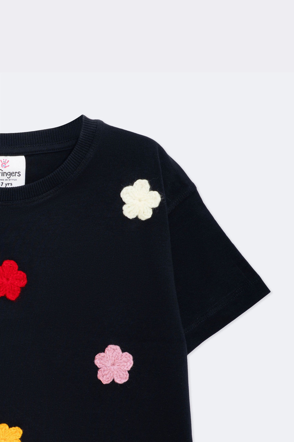 Black tee sleeve with small white and pink crochet flower appliques