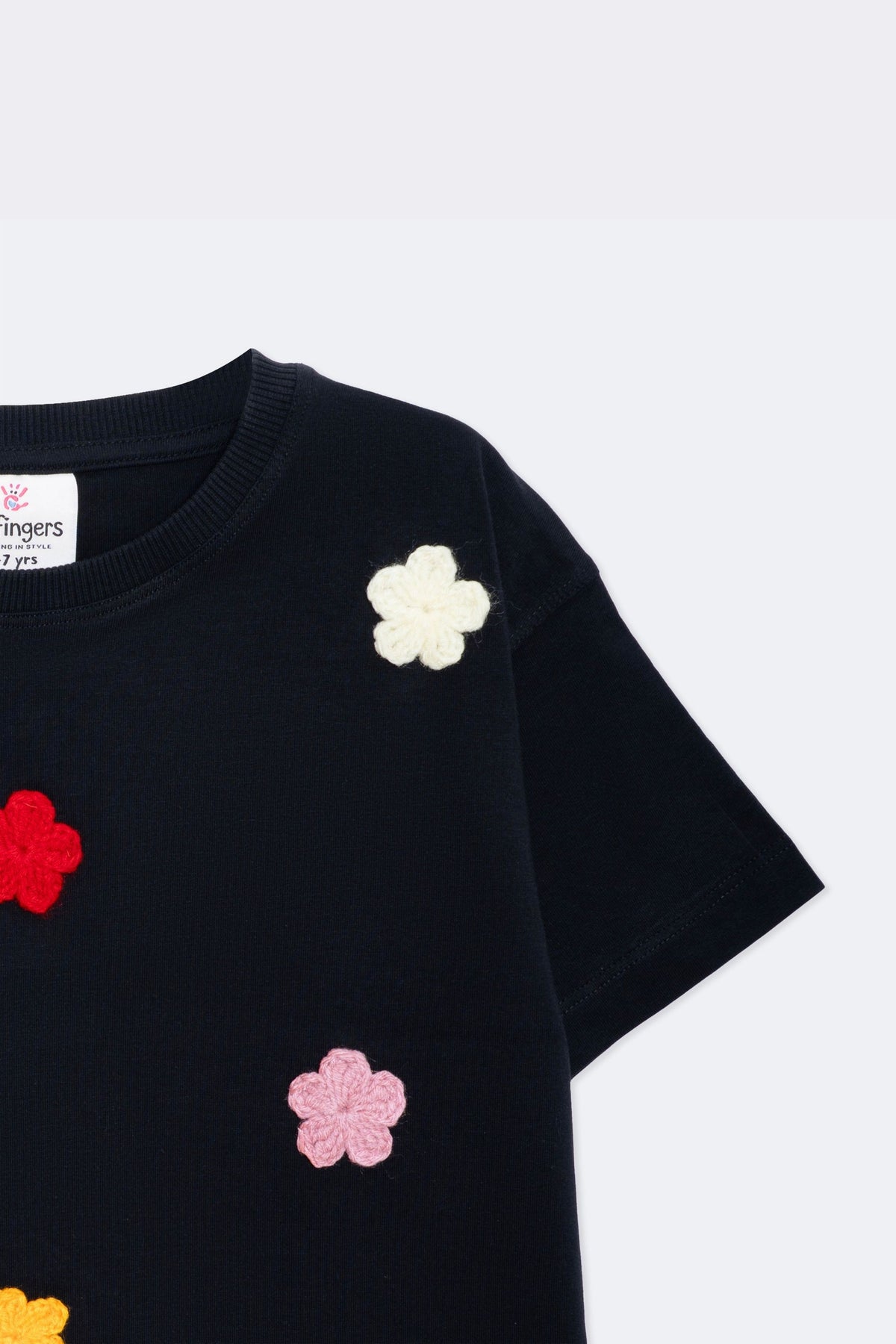 Black tee sleeve with small white and pink crochet flower appliques