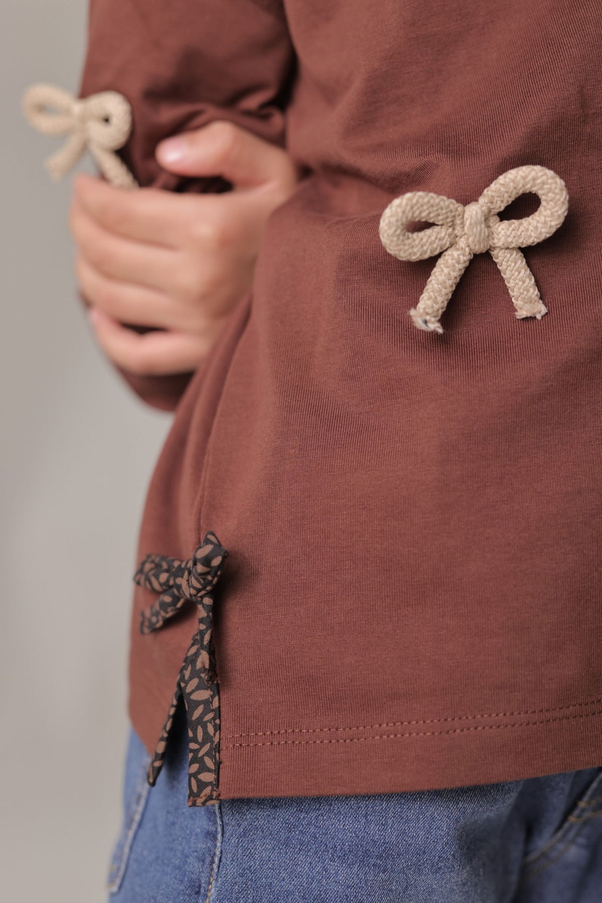 Dark brown tee showing side ribbon bow and beige bow applique at chest