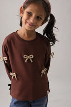 Dark brown long-sleeve kids' tee with beige bow appliques and side ribbon detail