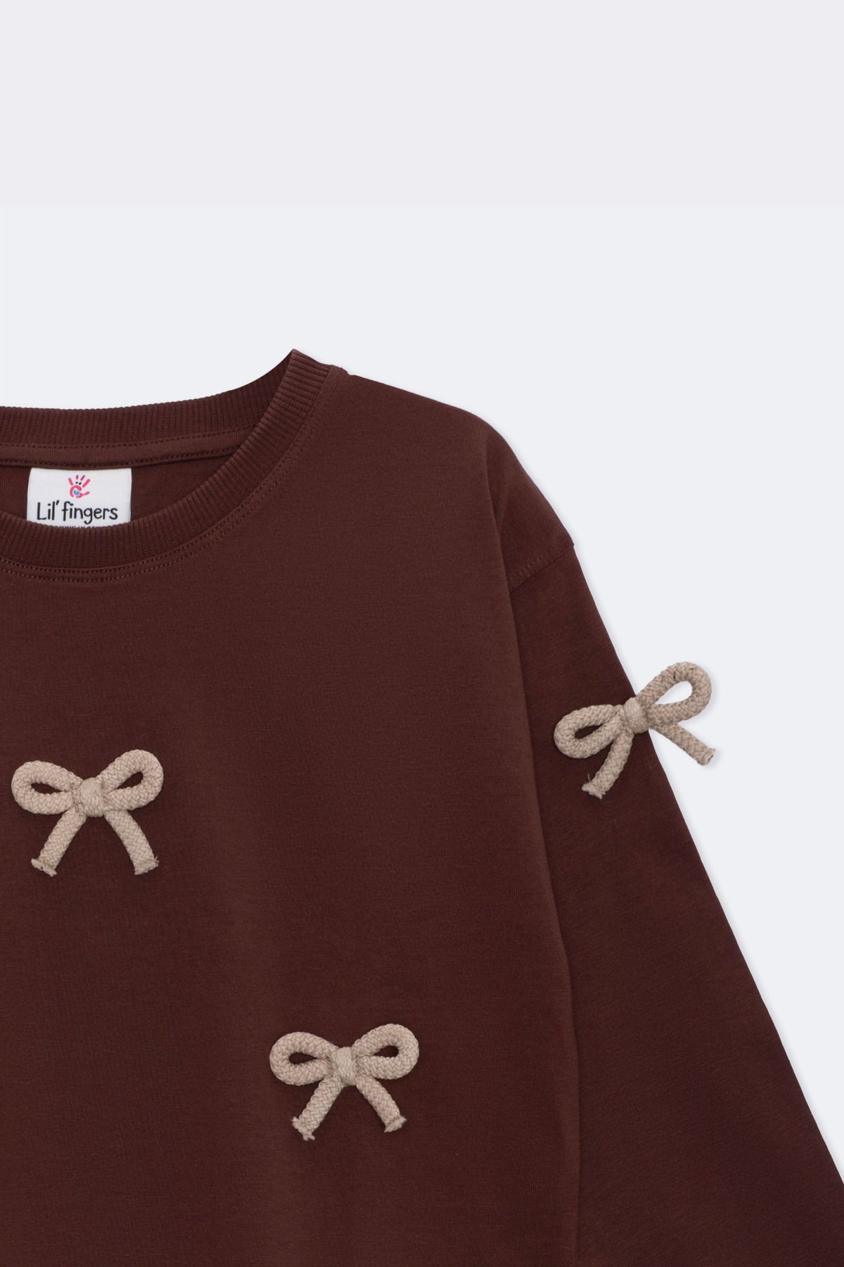 Dark brown long-sleeve tee with beige bow applique detail on sleeve and torso
