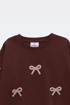 Dark brown long-sleeve tee with three beige bow appliques and crew neckline