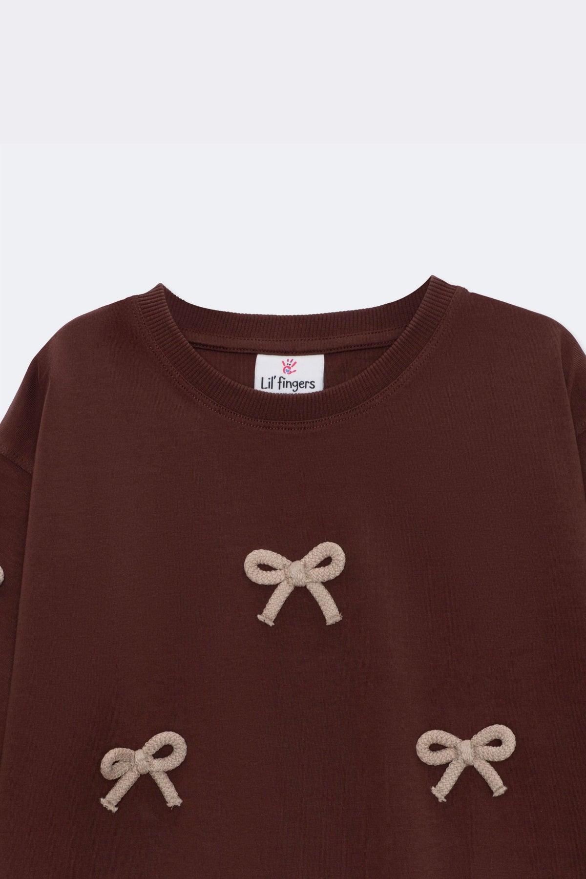 Dark brown long-sleeve tee with three beige bow appliques and crew neckline