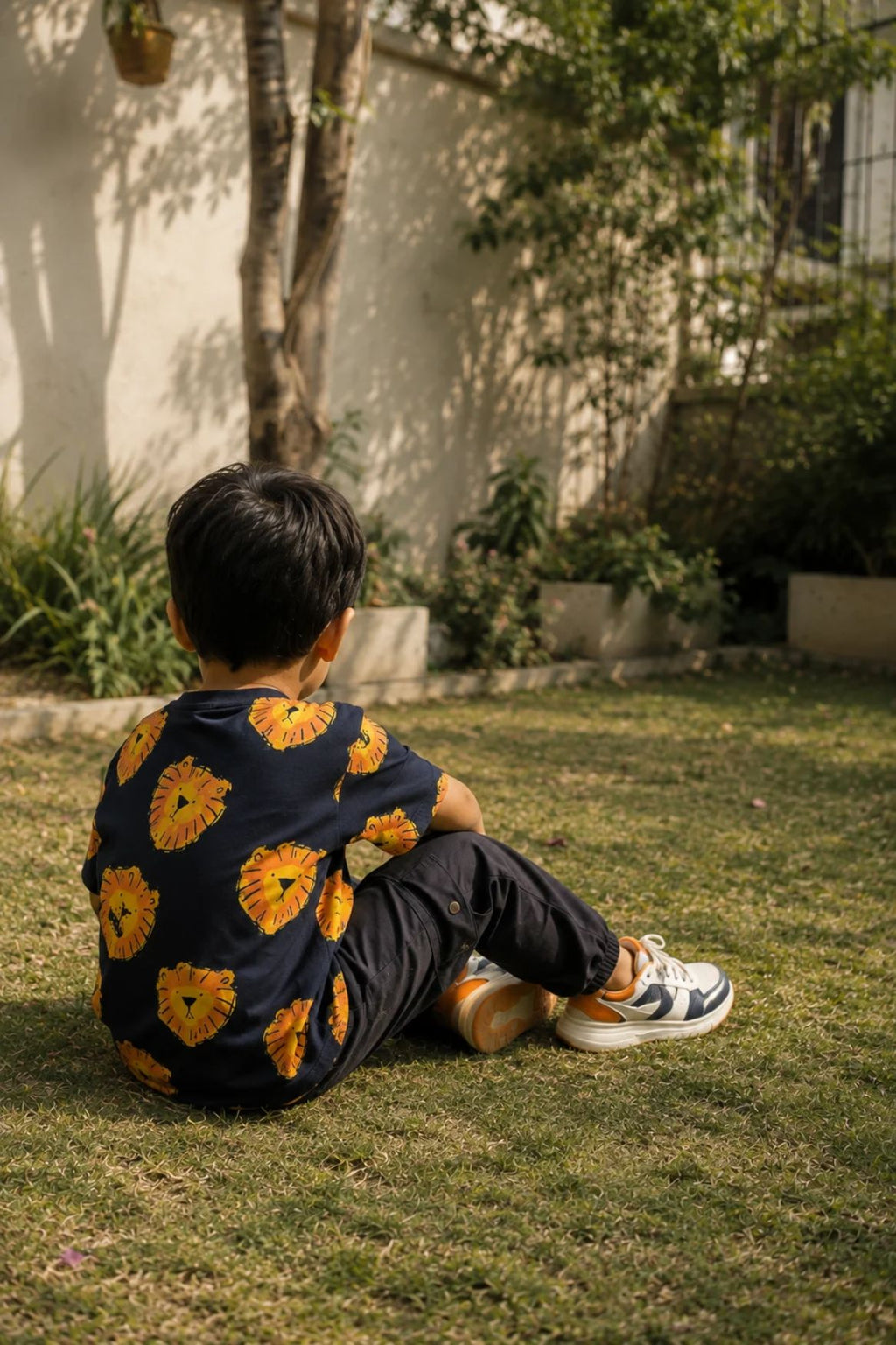 Dark navy oversized t-shirt with yellow and orange lion face print, worn by child