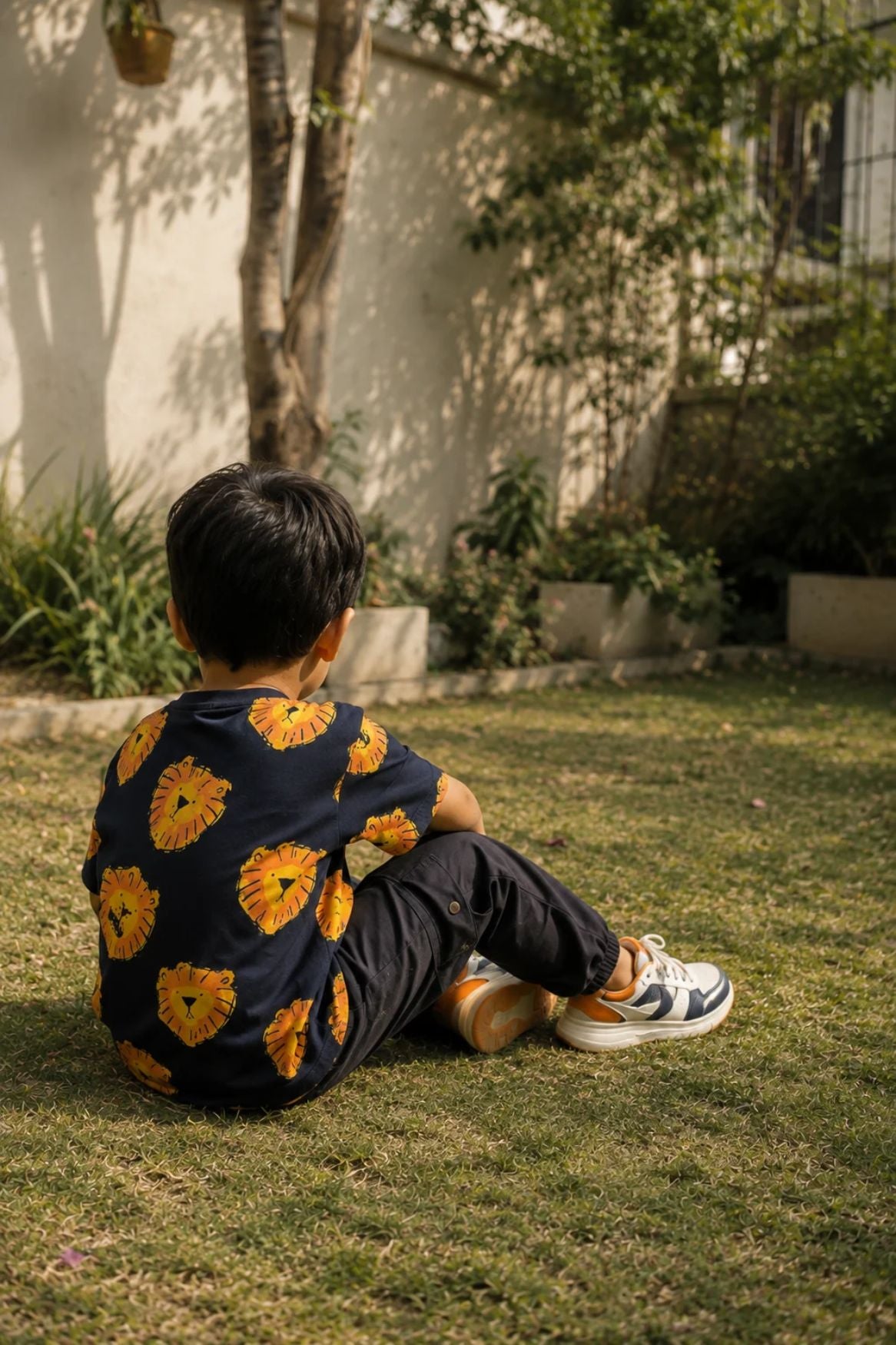 Dark navy oversized t-shirt with yellow and orange lion face print, worn by child