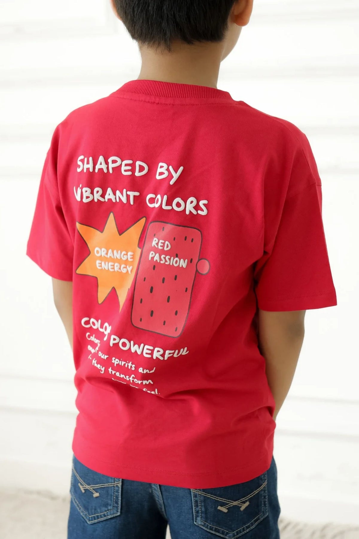 Red T-shirt worn by child, back print 'Shaped by Vibrant Colors'