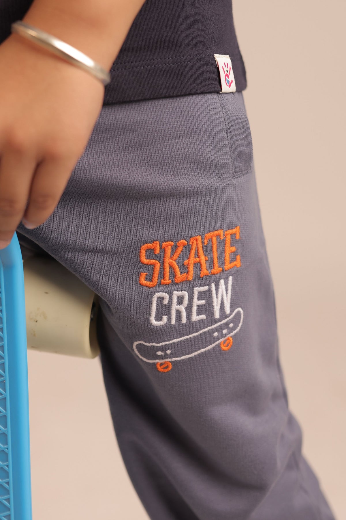 Denim blue track pants with skate-crew logo embroidery on thigh
