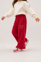 Red palazzo pants with elastic waist, ruffled hem, and heart patch embroidery
