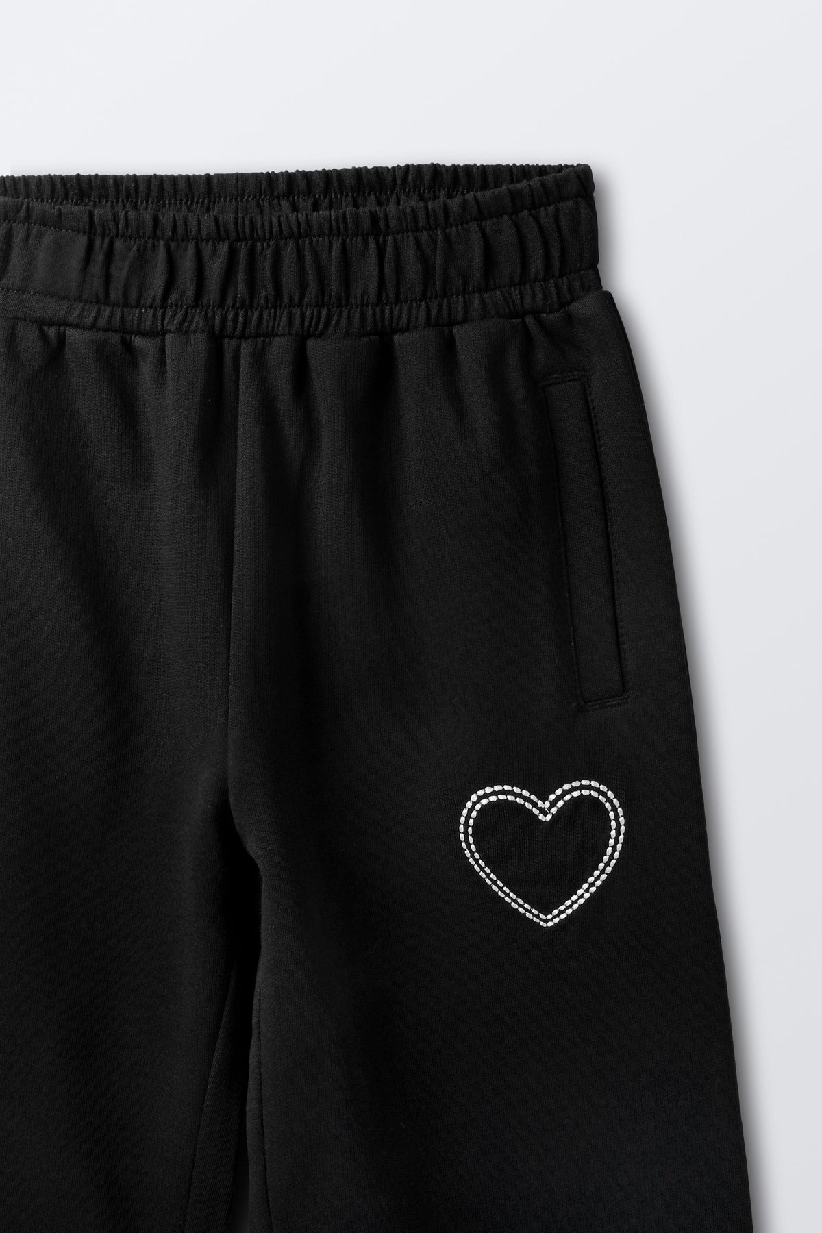 Black palazzo pants with rhinestone-style heart embroidery on leg