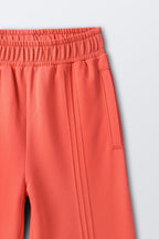 Coral palazzo pants with elastic waistband and vertical pintucked stripes
