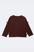 Dark brown boxy long-sleeve tee with beige bow appliques at sleeves and side ties